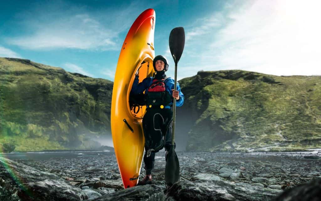 A kayaker holds up his kayak while out on expedition.